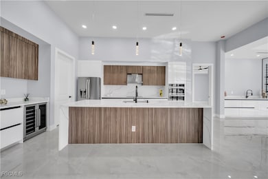 Kitchen with modern cabinets, brown cabinets, light stone counters, decorative light fixtures, and recessed lighting