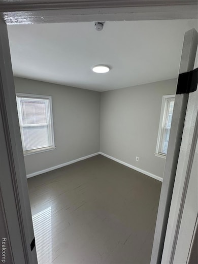 Empty room with baseboards and a smoke detector