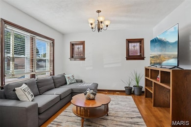 Living area with wood finished floors, a textured ceiling, a chandelier, and healthy amount of natural light