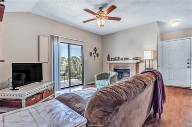 Living room featuring hardwood / wood-style floors, a textured ceiling, vaulted ceiling, and ceiling fan