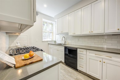 Kitchen featuring black dishwasher, a sink, backsplash, light wood finished floors, and recessed lighting
