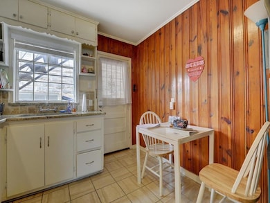 Kitchen with a sink, wooden walls, light tile pat