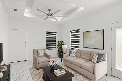 Living area featuring light marble finish flooring, a ceiling fan, and a tray ceiling
