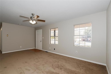 Empty room featuring light colored carpet and ceiling fan