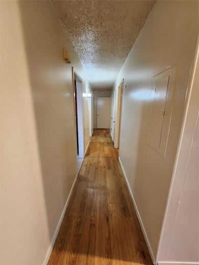 Hall with a textured ceiling, hardwood / wood-sty