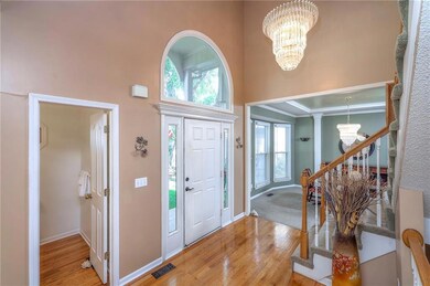Foyer featuring a chandelier, light wood-style flooring, a high ceiling, plenty of natural light, and stairs