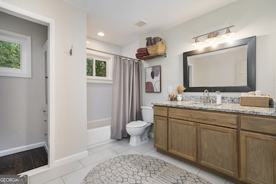 Primary Suite with a Large Walk-In Closet and Ensuite Bathroom with Stone-and-Wood Vanity and Shower/Tub Combo