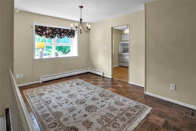 Unfurnished room with a chandelier and a baseboard radiator