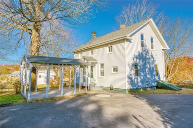 Rear view of home showing large driveway and cover