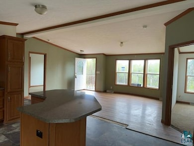 Kitchen with ornamental molding, dark countertops, a center island, brown cabinetry, and open floor plan