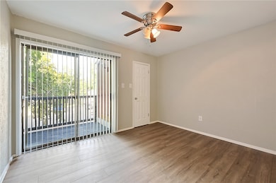 * Front bedroom with wood finished floors, balcony, walk-in closet and a ceiling fan