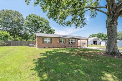 View of front facade with a shed, brick siding, concrete driveway, and a carport