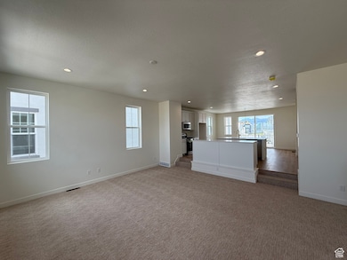 Unfurnished living room featuring light colored carpet, healthy amount of natural light, recessed lighting, and a textured ceiling