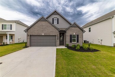Craftsman house with brick siding, driveway, a front yard, a garage, and central air condition unit