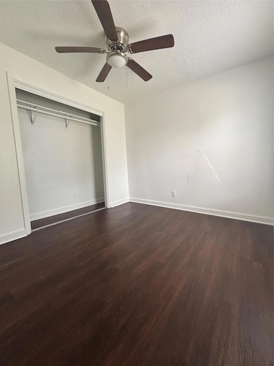 Unfurnished bedroom with baseboards, dark wood fi
