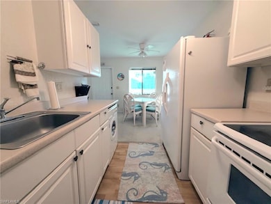 Kitchen with white cabinets, electric stove, light countertops, and light wood-style floors