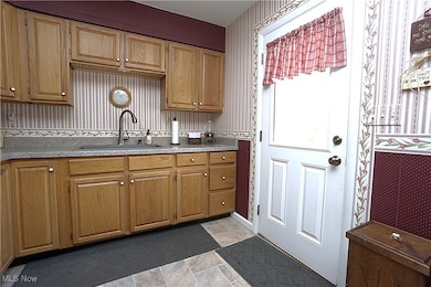 Kitchen with wallpapered walls, light countertops, and brown cabinetry