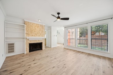 Unfurnished living room with a fireplace, light wood-type flooring, a ceiling fan, ornamental molding, and built in features