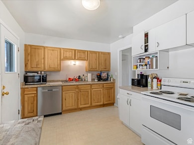 Kitchen featuring appliances with stainless steel finishes, light flooring, open shelves, and light stone counters