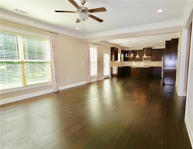 Unfurnished living room featuring ornamental molding, ceiling fan, and hardwood / wood-style floors