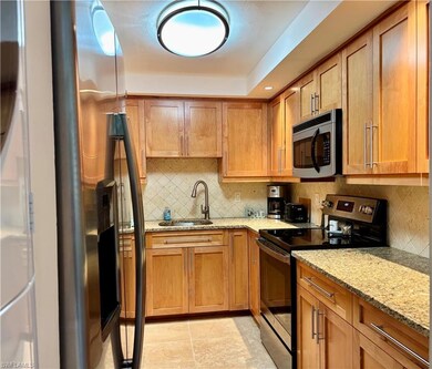 Kitchen featuring tasteful backsplash, light stone