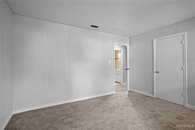 Carpeted empty room with baseboards and visible ve