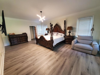 Bedroom featuring ornamental molding, wood finished floors, and a chandelier