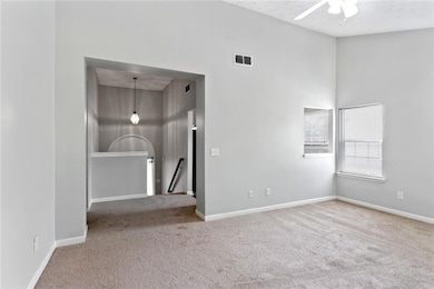 Spare room featuring carpet, a ceiling fan, and a high ceiling