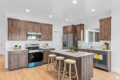 Kitchen featuring appliances with stainless steel finishes, light wood-style flooring, a breakfast bar area, recessed lighting, and a kitchen island