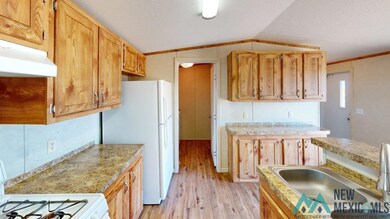 Kitchen featuring light wood-style flooring, white appliances, light countertops, vaulted ceiling, and under cabinet range hood