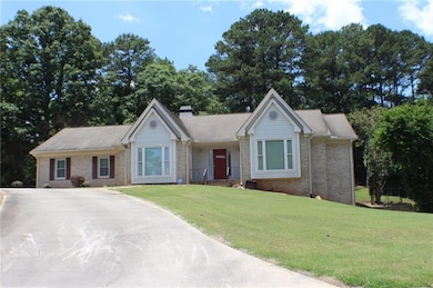 Ranch-style house featuring brick siding, a chimney, a front lawn, and concrete driveway
