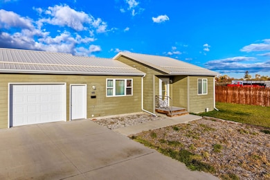 Ranch-style home with a metal roof, driveway, and a garage