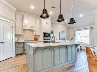 Kitchen featuring appliances with stainless steel finishes, a kitchen breakfast bar, hanging light fixtures, and light hardwood / wood-style floors