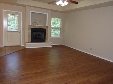 Living room features gas log fireplace, trey ceiling and laminate wood flooring.