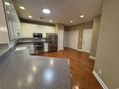 Kitchen featuring stainless steel appliances, a sink, dark countertops, white cabinets, and a textured ceiling