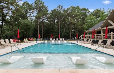 Community pool with a patio and view of scattered trees