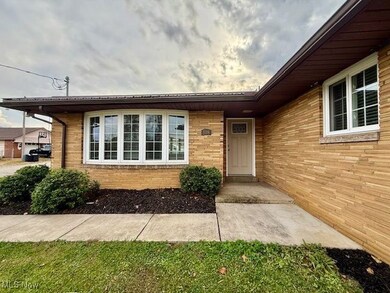 View of exterior entry with brick siding and a yard