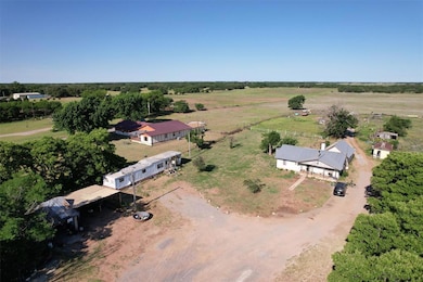 Main House (foreground, center) – A single-story house with a gray metal roof and a covered front porch. There is a concrete walkway leading to the front steps.