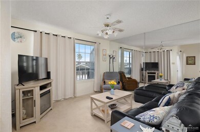Living area with light carpet, ceiling fan, and a textured ceiling