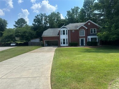 Traditional-style house featuring a garage, concrete driveway, brick siding, and view of scattered trees