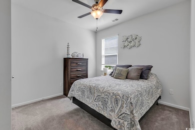 Carpeted bedroom with ceiling fan and baseboards