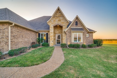 View of front of house with a shingled roof, brick siding, and a front yard