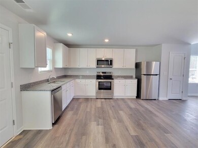 Kitchen featuring appliances with stainless steel finishes, white cabinets, a healthy amount of sunlight, and sink