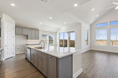Kitchen featuring gray cabinetry, lofted ceiling, recessed lighting, dark wood finished floors, and a kitchen island with sink