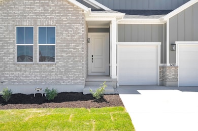 Property entrance with board and batten siding, driveway, brick siding, and an attached garage