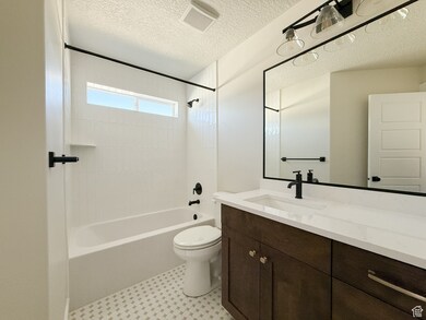 Bathroom featuring shower / washtub combination, a textured ceiling, and vanity