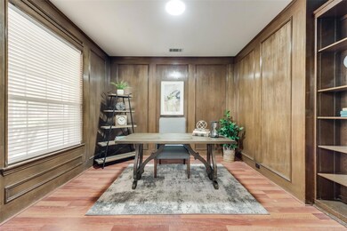 Home office with wooden walls and light hardwood / wood-style flooring