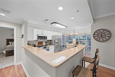 Kitchen with appliances with stainless steel finishes, ornamental molding, light stone countertops, a breakfast bar, and white cabinetry