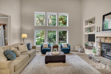 Living room with a towering ceiling, healthy amount of natural light, built in features, carpet flooring, and a stone fireplace