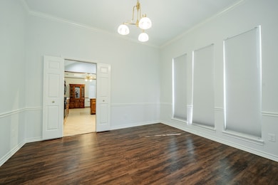 Unfurnished room featuring a chandelier, dark wood-type flooring, and crown molding
